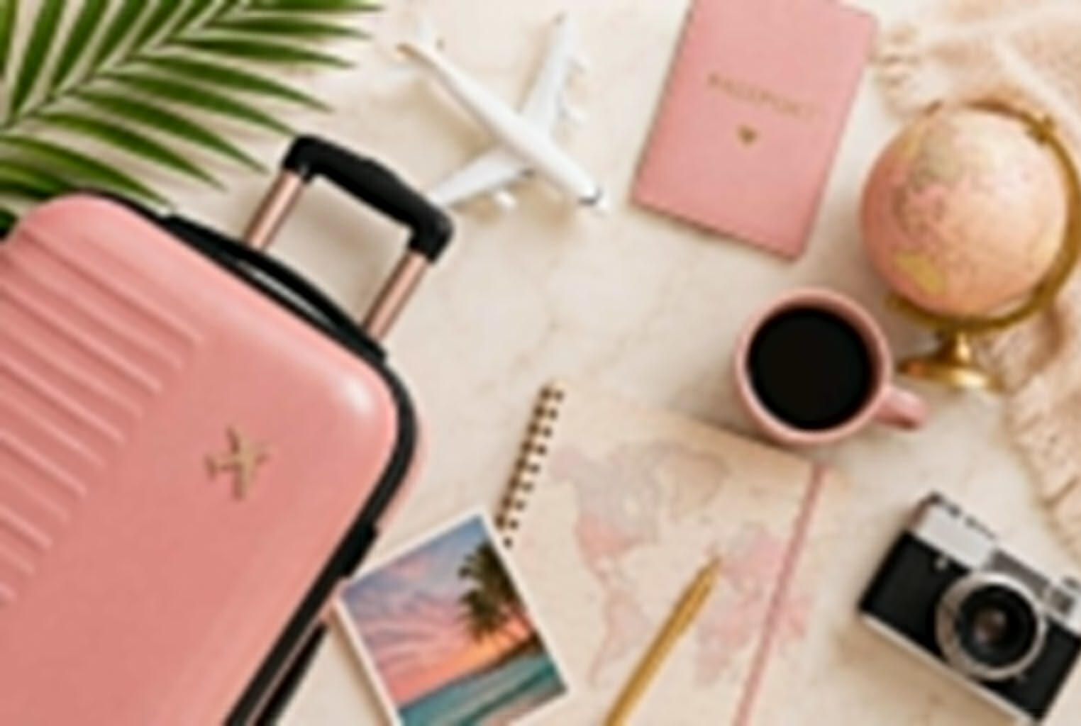 Elementos de viaje sobre escritorio: valija, pasaporte, avión, cuaderno y accesorios de planificación.